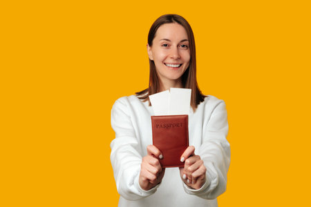 Portrait of a cheerful young woman holding a passport with flight tickets.の写真素材