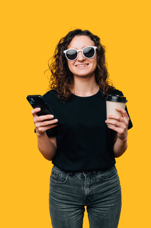 Young Woman with Coffee-to-Go and Smartphone - Modern Lifestyle in a Studio Shotの写真素材