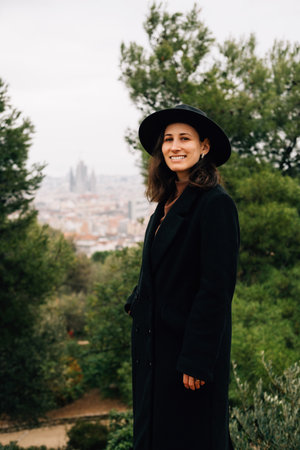 Outdoors vertical portrait of a smiling woman wearing black hat in Park Guell.の写真素材
