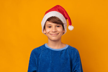 Portrait of smiling young boy wearing red santa claus hat over yellow backgroundの写真素材