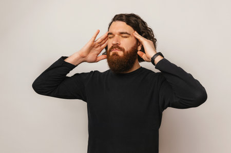 Photo of bearded man standing over white background and thinking about somethingの写真素材