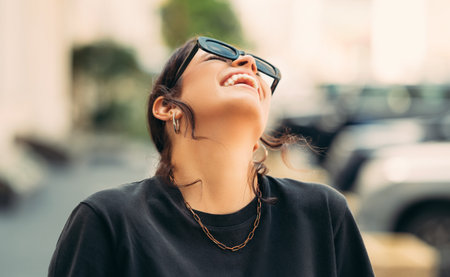 Outdoors portrait of a young laughing woman in black walking on the street.の写真素材