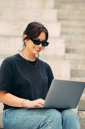 Young smiling woman works on the laptop while holding it on her knees.の写真素材