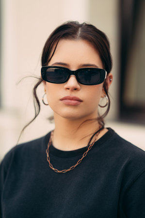 Vertical outdoors portrait of a serious young woman wearing sunglasses.の写真素材