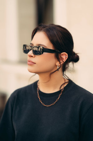 Vertical outdoors portrait of a serious woman looking aside wearing sunglasses.の写真素材