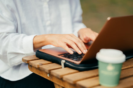 Female hands are typing on a laptop outdoors working and enjoying morning time.の写真素材