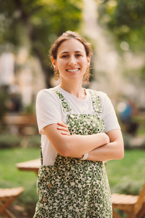 Vertical portrait of a young woman smiling at the camera with arms crossed.の写真素材