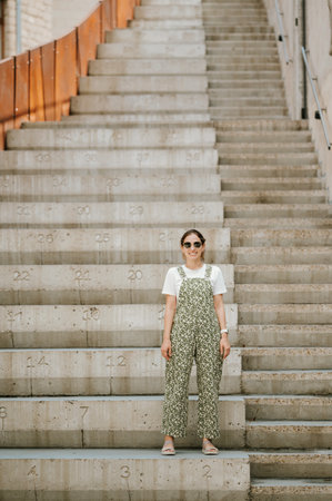 Full length portrait of a young woman in green standing on concrete stairs.の写真素材
