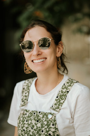 Young cheerful woman wearing cool sunglasses is smiling at the camera.の写真素材