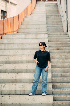 Beautiful full length shot of a smiling woman sitting on concrete stairs.の写真素材