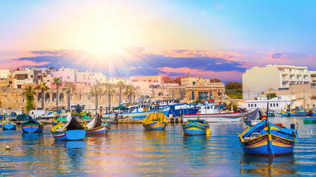 Beautiful panorama of Valletta harbor in Malta, with boats and architecture illuminated by sunset lightの写真素材
