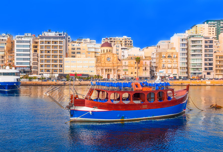 Beautiful traditional architecture and a classical boat on the famous harbor of Malta, at sunsetのeditorial素材