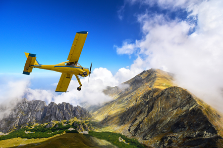 Old and vintage cessna plane flying above Carpathian mountain peaks in Romaniaの写真素材