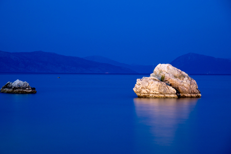 Beautiful landscape over the sea with a stone illuminated in night in Corfu island, Greeceの写真素材