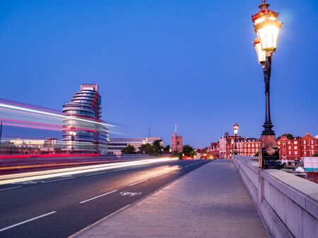 Red double decker bus trails on Putney bridge agains blue sky in Londonの写真素材