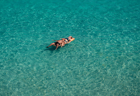Lecce, Italy - August 11, 2018: Couple of people floating on the blue clear sea in a sunny day in...