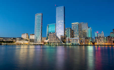 Financial district of London city Canary Wharf reflected on the Thames river at blue hour in Englandの写真素材