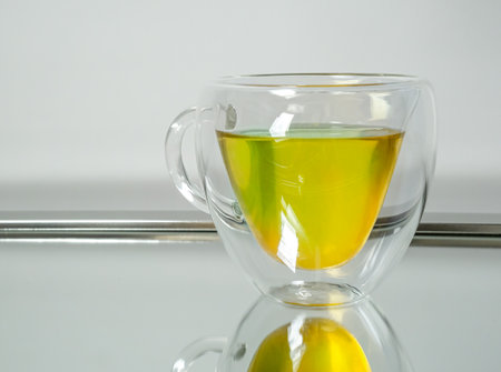 A glass cup of lemon herbal tea reflected on a mirrorの写真素材