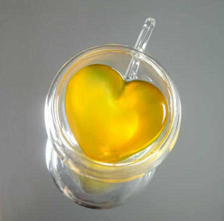 Top view of a transparent heart-shaped teacup with yellow tea liquidの写真素材
