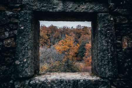 A stone window overlooking the autumnの写真素材