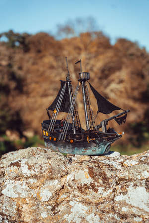 A toy pirate ship on some rocks on a summer day in the middle of natureの写真素材