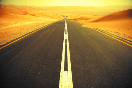Winding black asphalt road through the sand dunes of Liwa oasis, United Arab Emiratesの写真素材
