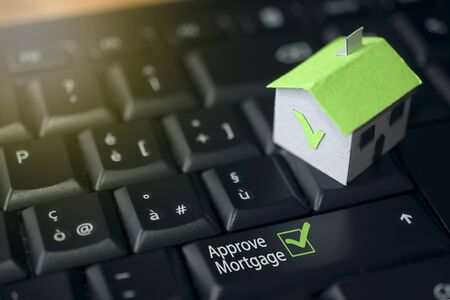 Mortgage and loan concept: paper house on a computer keyboardの写真素材