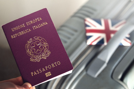 An italian passport holded over a suitcase with an english id holder on it: brexit conceptの写真素材