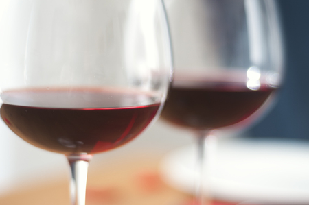 Blurred wine glasses on a table with a plateの写真素材