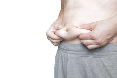 Man with sport shorts pulls his belly fat, body isolated to use a custom backgroundの写真素材