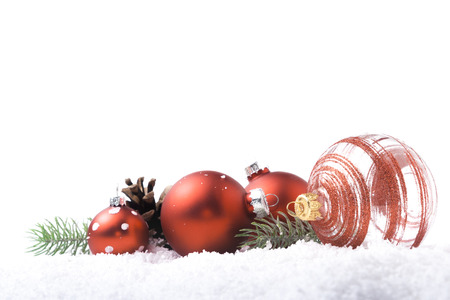 Red Christmas balls, pine cone and pine branch on the snow isolated, Christmas background or frameの写真素材