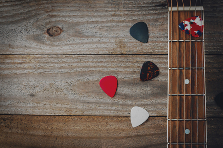 Acoustic guitar fretboard and some guitar picks on wooden tableの写真素材