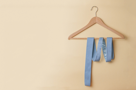 Tie rolled up on a wooden hanger, hanging on a yellow wallの写真素材