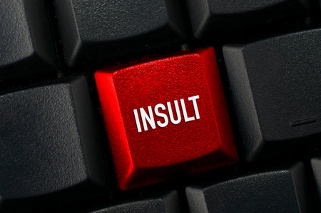 Hate speech concept: Black keyboard with a red key and the insult word