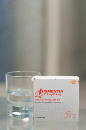 Carrara, Italy - August 08, 2019 - Box of Augmentin pills (amoxicillin, clavulanic acid ) on a glass...
