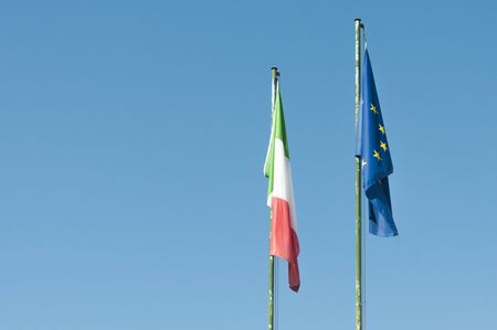 Italian and european flags with blue sky as background, copy spaceの写真素材
