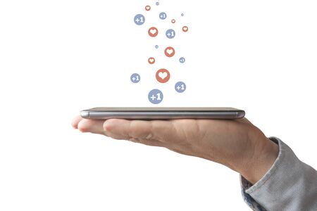 Man holds smartphone from which hearts and thumbs up come out on top of his palmの写真素材