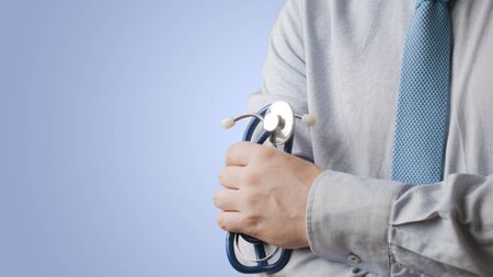 Doctor in shirt and tie with a stethoscope on blue background with lot of copy space, 16:9 ratioの写真素材