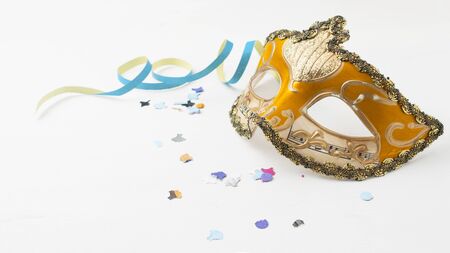 Orange carnival mask on white table with some stream and confettiの写真素材