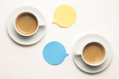 Two cup of coffee on a white wooden table with orange and blue balloons with copy spaceの写真素材