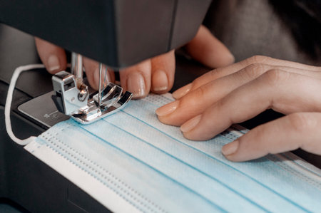 Woman sewing a surgical mask at home during quarantine. Surgical mask are used to prevent contagion...