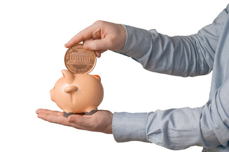 Businessman in shirt try to put a giant american penny into a small piggy bank. Isolated on white...