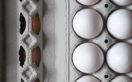 White orgnanic eggs on disposable egg tray made of pressed cardboard on wooden table, flat lay