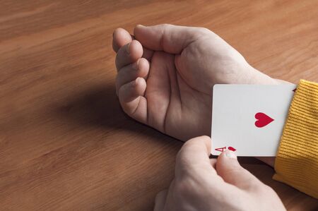 Man in yellow sweater shows an ace up his sleeveの写真素材