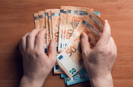 Man gather euro banknotes from a wooden table