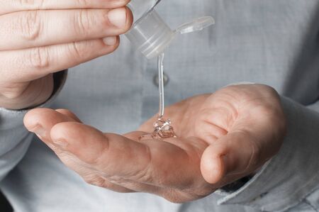 Businessman disinfects his hands using a pocket sanitizing gelの写真素材