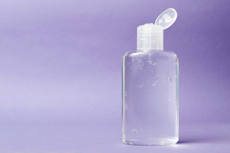 Bottle of antiseptic and antibacterial hand gel sanitizer on purple background