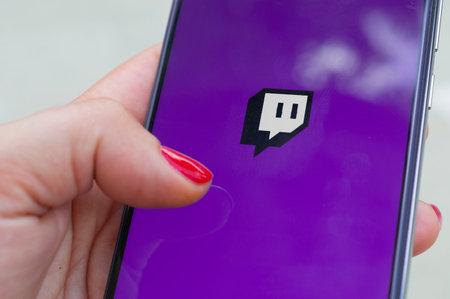 Carrara, Italy - July 6, 2020: Woman run Twitch application on a smartphone outdoor. Twitch is a live streaming platform owned by Amazonのeditorial素材