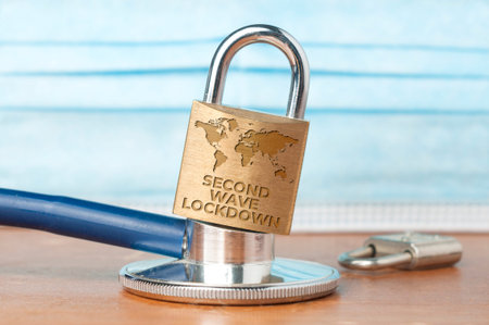 Covid-19 lockdown concept: a lock over a stethoscope with a surgical mask as background and the...