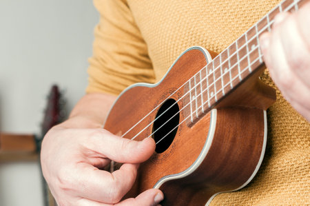 Detail of man with yellow sweater playing a ukuleleの写真素材